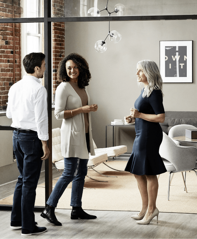 A Century 21 agent standing and speaking with a man and woman client in a Century 21 office