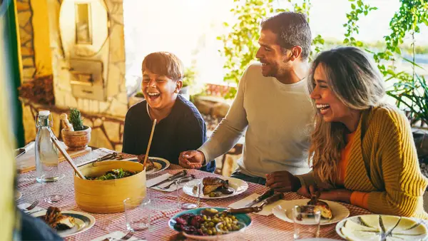 Familia y amistades feliz compartiendo una comida en el patio trasero de su casa