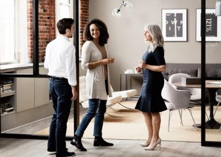 Three business people standing and chatting in an office